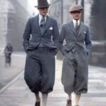 Two men walking in a city wearing vintage early 20th century suits and knickerbockers.